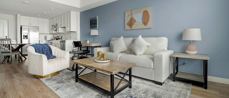 A modern living room with a white sofa, a coffee table, and a dining area with a table and chairs.