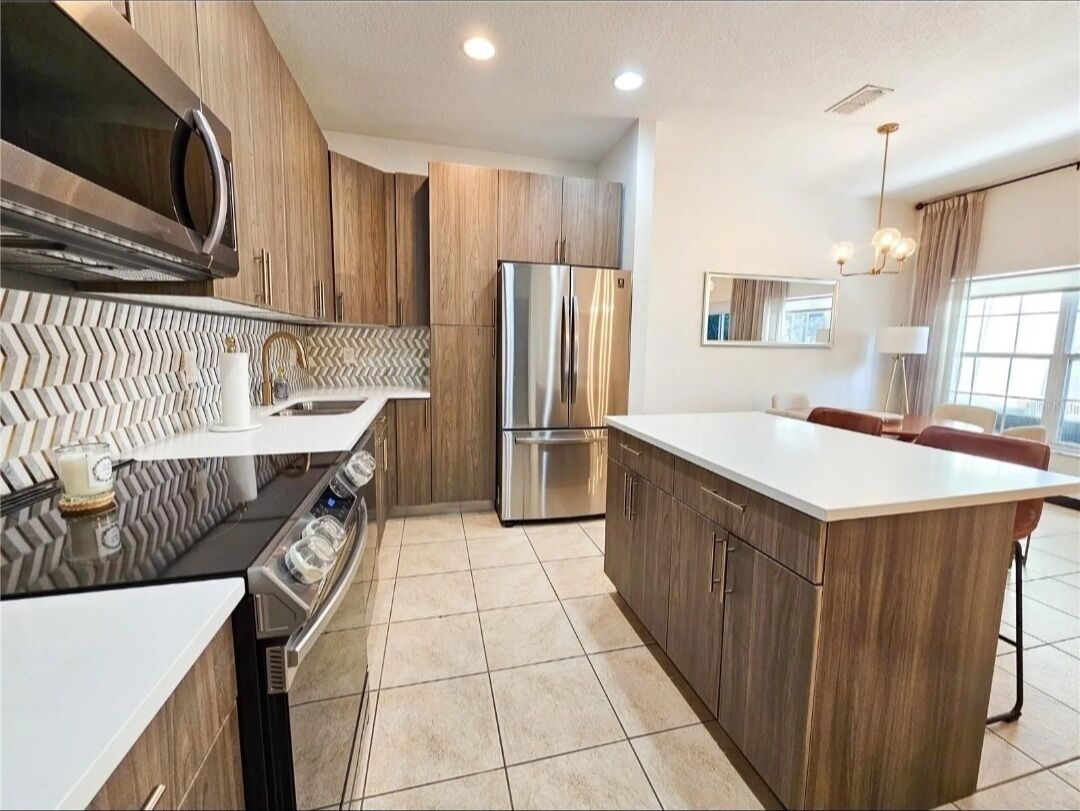 A modern kitchen with a central island, stainless steel appliances, and wooden cabinetry.