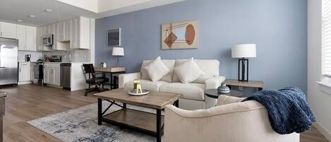 A modern living room with a sofa, coffee table, and a dining area with a lamp.