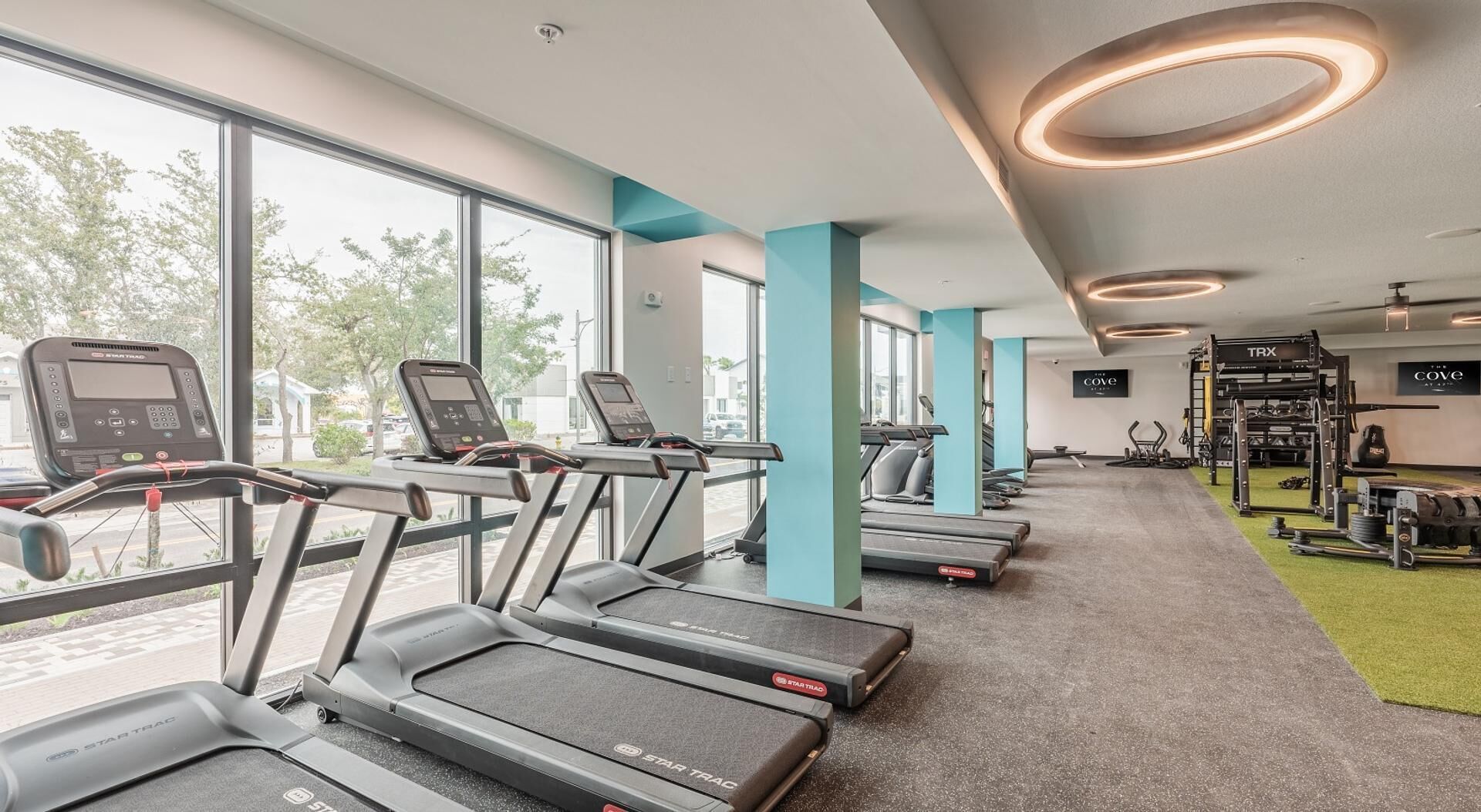 Une salle de sport équipée de tapis de course, d’appareils de musculation et d’un téléviseur fixé au mur.