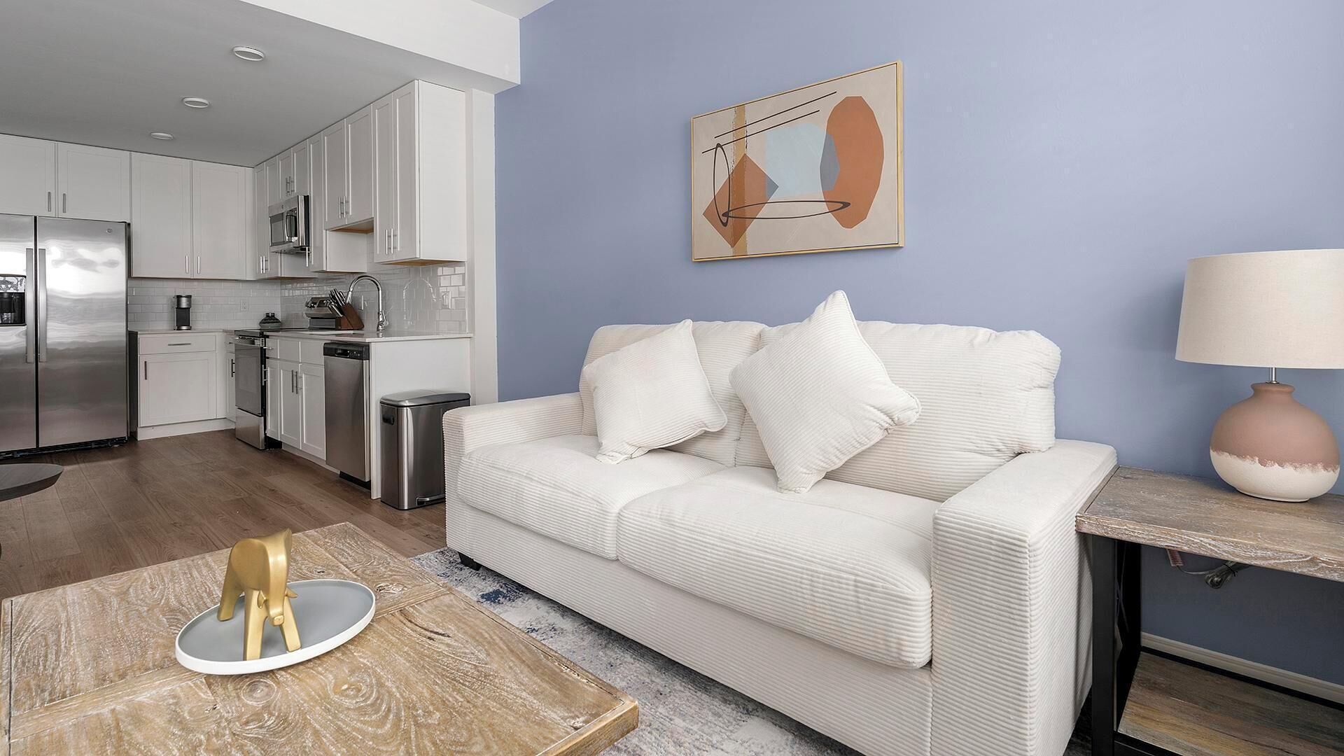 Uma sala de estar moderna com um sofá branco, uma mesa de centro e uma luminária.
