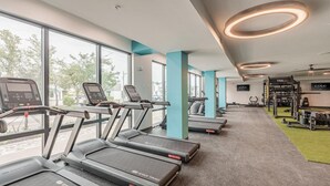 A gym with treadmills, weight machines, and a wall-mounted TV. - Landing | Spectacular 1BD, Clubhouse, Pool (Cape Coral)