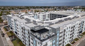 A multi-story hotel with a rooftop terrace, parking garage, and a view of the surrounding cityscape.