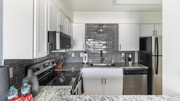 A modern kitchen with white cabinets, a stainless steel refrigerator, and a granite countertop. - Landing | Beautiful 1BD in Maryvale Village (Phoenix)