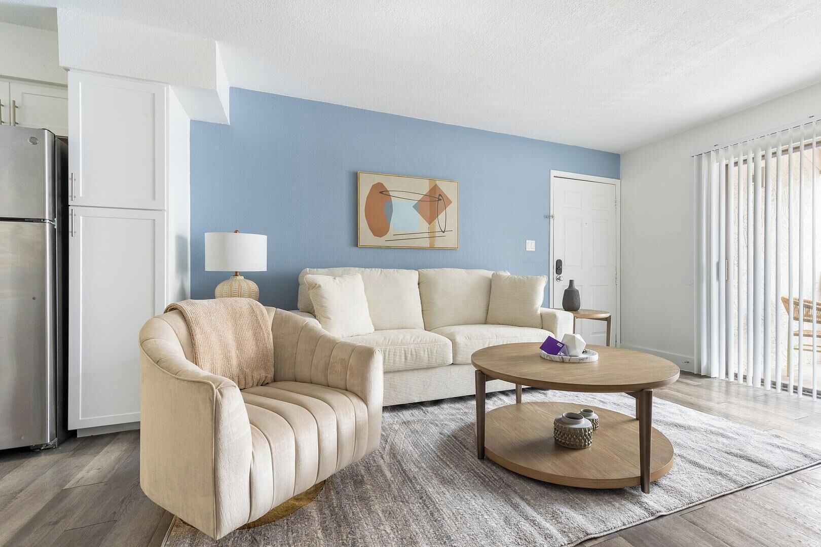 Ein modernes Wohnzimmer mit einem beigen Sofa, einem runden Couchtisch und einem Gemälde an der Wand.
