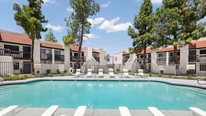 A swimming pool with lounge chairs and a building with a tiled roof. - Landing | Chic 2BD in Maryvale Village (Phoenix)