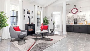 Uma sala de estar moderna com lareira, sofá cinza, almofadas vermelhas e uma mesa de centro.