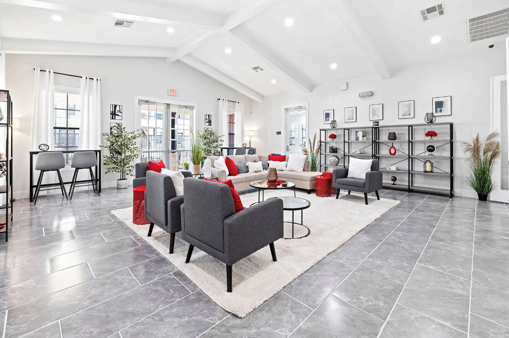 A spacious lobby with modern furniture, a large bookshelf, and a potted plant.