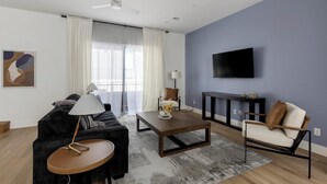 Una sala de estar moderna con un sofá, un sillón, una mesa de centro y un televisor de pantalla plana montado en la pared.