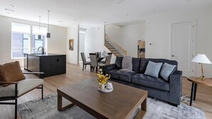 Una sala moderna con un sofá gris oscuro, una mesa de centro de madera y un comedor con una silla gris.