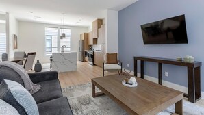 Ett modernt vardagsrum med en soffa, ett soffbord och en tv som är monterad på väggen.