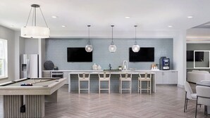 A modern kitchen with a bar area, a pool table, and a flat-screen TV mounted on the wall. - Landing | Stunning 1BD, Gym, Pool (The Villages)