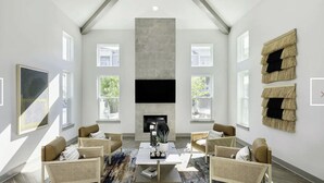 Un salón amplio con techo alto, ventanas grandes, televisor de pantalla plana y chimenea.