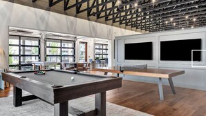 Uma mesa de bilhar em um espaço com janelas amplas e um design de teto moderno.