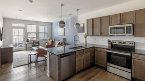 A modern kitchen with a central island, stainless steel appliances, and wooden cabinets.