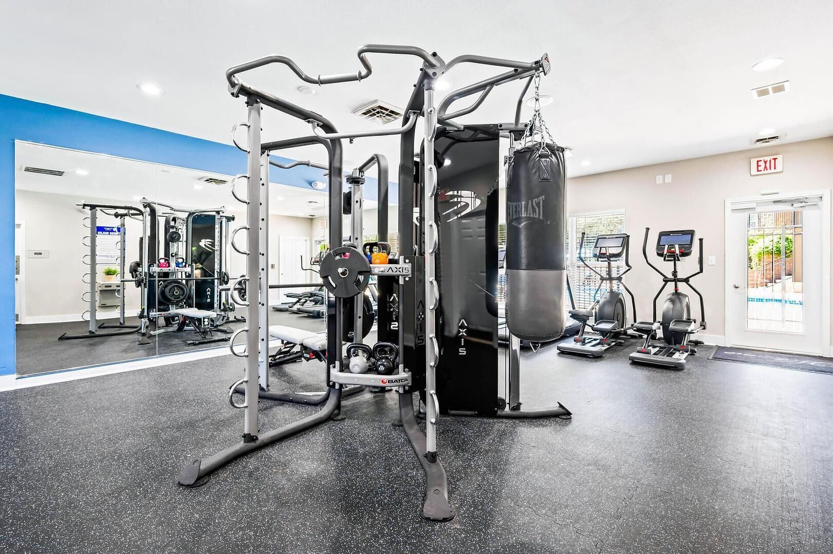 A gym with various exercise equipment, including a squat rack, a bench press, and a punching bag.