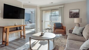 A living room with a TV, a wooden table, a round coffee table, a sofa, and a chair.