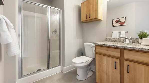 A modern bathroom with a glass shower enclosure, a toilet, and wooden cabinets.