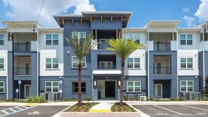 A multi-story residential building with balconies, a central entrance, and two palm trees in front. - Landing | Spectacular 1BD, Gym, Pool (Bellview)