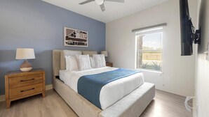 A bedroom with a bed, bedside tables, a ceiling fan, a window, and a wall-mounted TV. - Landing | Chic 2BD, Pool, Gym (Lockhart)
