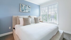 Un dormitorio con una cama grande, un ventilador de techo, una ventana con persianas y una obra de arte en la pared.