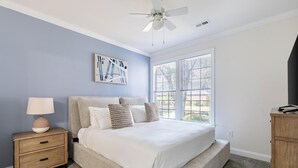 Un dormitorio con cama, mesita de noche, lámpara y cómoda.