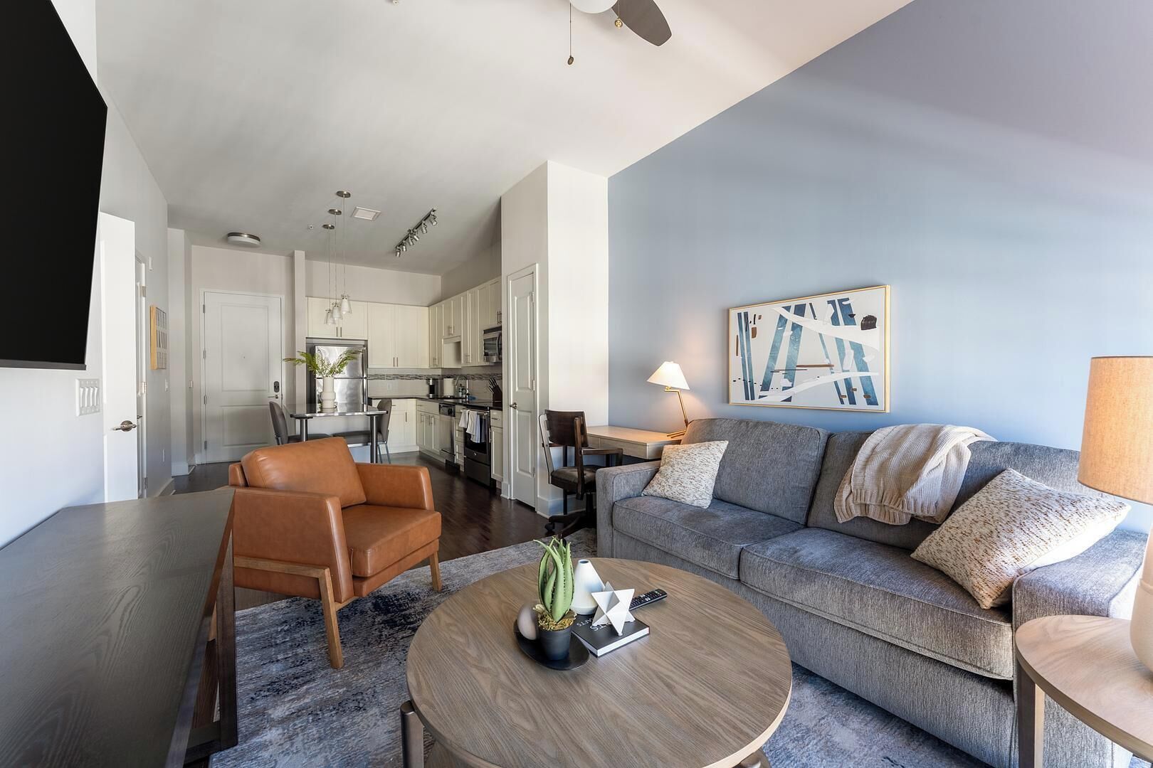 A modern living room with a sofa, coffee table, and a dining area with a table and chairs.
