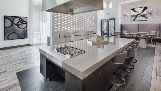 Una cocina moderna con una isla central, taburetes de bar e iluminación contemporánea.