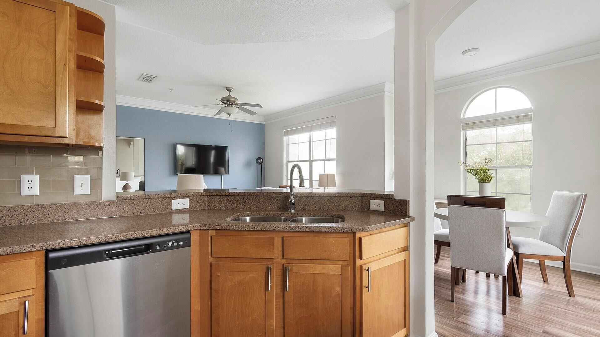 A modern kitchen with granite countertops, wooden cabinets, and a built-in dishwasher.
