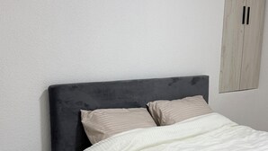 A bedroom with a bed, a nightstand, a wardrobe, and a herringbone-patterned wooden floor. - Oficerski apartment (Bitola)
