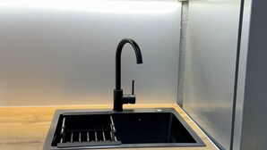 A kitchen with a black sink, wooden countertop, and a stainless steel refrigerator. - Oficerski apartment (Bitola)