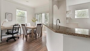 A modern kitchen with a granite countertop, a built-in sink, and a dining area with a wooden table and chairs. - Landing | Beautiful 1BD, Yoga Studio (Jacksonville)
