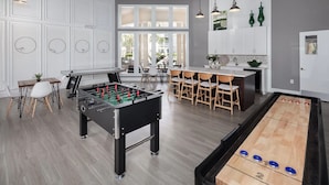 Un'ampia zona giorno con tavolo da calcio, tavolo da shuffleboard e angolo pranzo con bancone.