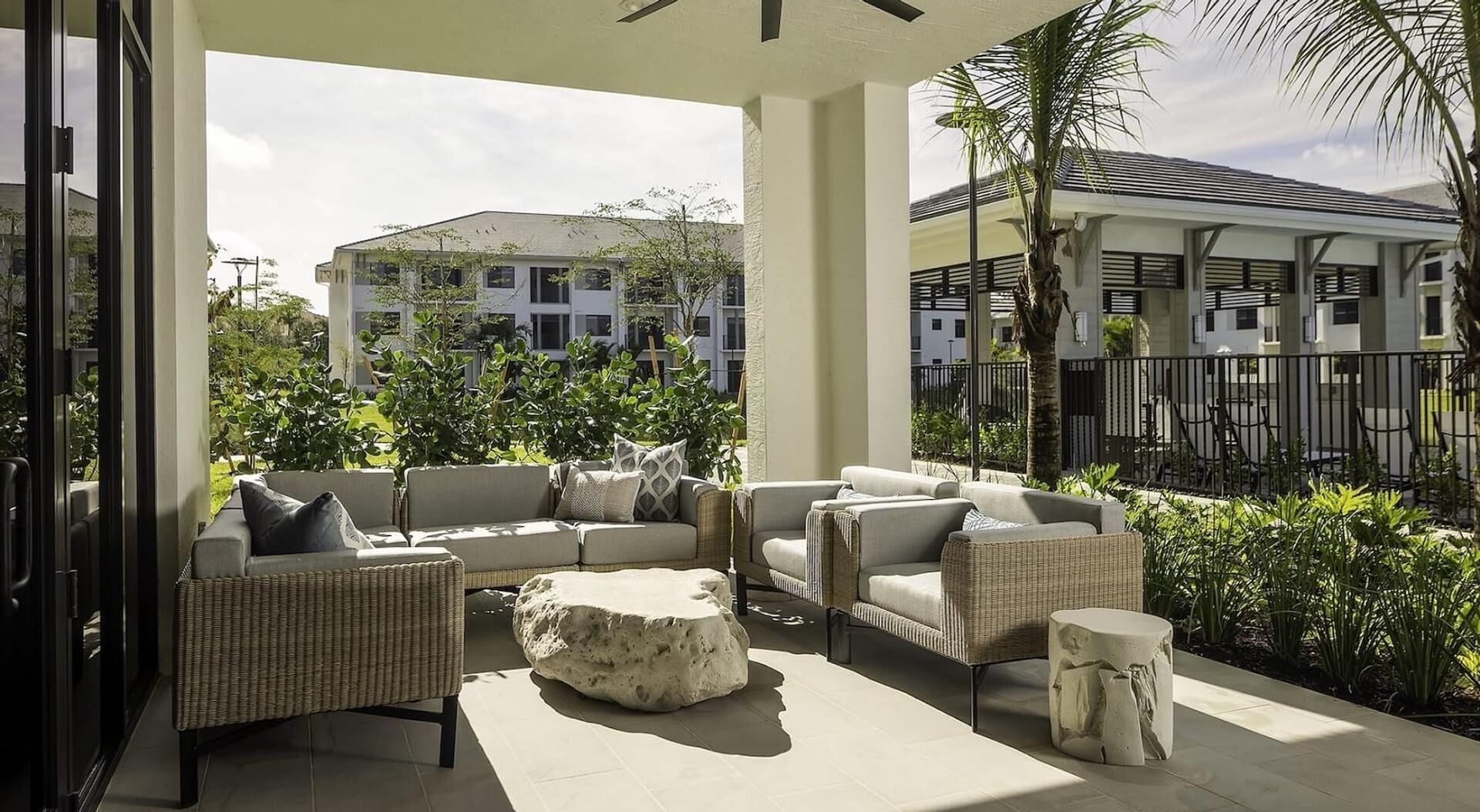 A covered outdoor seating area with wicker furniture and a stone accent piece.