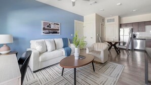 A modern living room with a sofa, armchair, coffee table, and a painting on the wall. - Landing | Incredible 1BD, Gym, Pool (Lockhart)