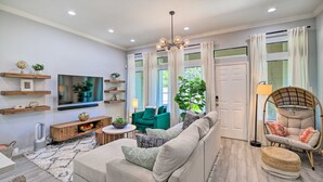 Un salon moderne avec un canapé, un téléviseur et des plantes décoratives.