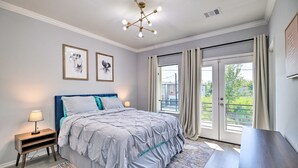 Une chambre à coucher comprenant un lit, des tables de chevet, un luminaire au plafond et une fenêtre avec des rideaux.