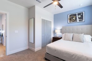 A bedroom with a bed, a nightstand, a lamp, a ceiling fan, and a door. - Landing | Beautiful 1BD, Game Room, Pool (Freeport)