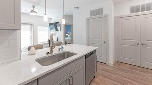 Une cuisine moderne dotée d’un grand îlot central, d’appareils électroménagers en acier inoxydable et d’un grand miroir.