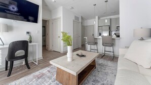Un salon moderne doté d’un téléviseur à écran plat, d’une table basse, d’un canapé et d’un coin repas avec des chaises.