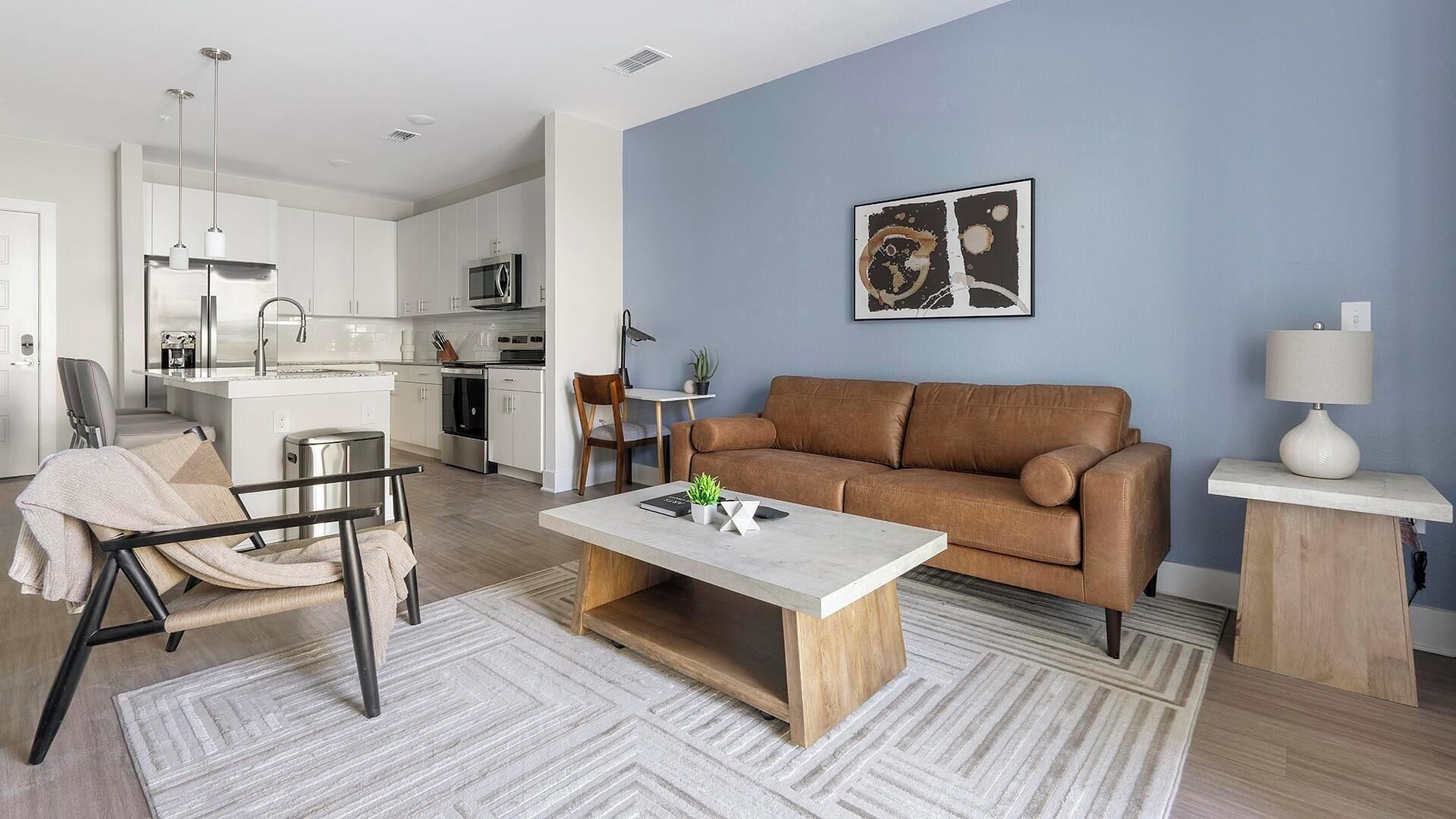 Una sala de estar moderna con un sofá marrón, una mesa de centro y un comedor con una cocina al fondo.