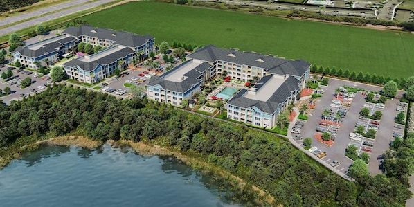 An aerial view of a hotel complex with multiple buildings, a swimming pool, and a parking lot.