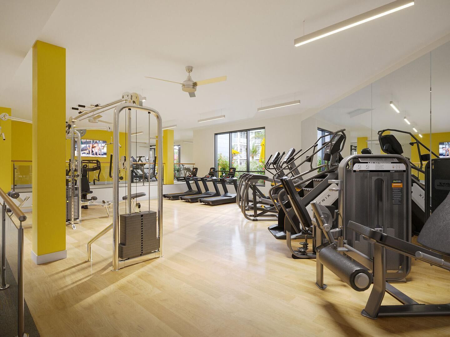 Un gimnasio con máquinas de cardio, equipo de levantamiento de pesas y un ventilador de techo.