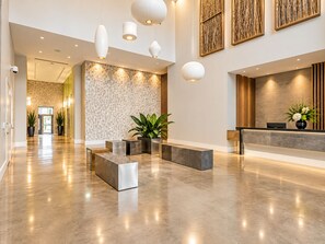 A modern reception area with a polished concrete floor, a reception desk, and a seating area with planters. - Luxury Loft in Downtown Miami - Rooftop Pool, Gym & Skyline Views (Miami)