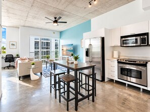 A modern kitchen with stainless steel appliances, a dining area with a table and chairs, and a large window with a view of the outdoors. - Luxury Loft in Downtown Miami - Rooftop Pool, Gym & Skyline Views (Miami)