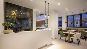 A modern reception area with a marble wall, a reception desk, and seating arrangements. - Anesea City (Heraklion)