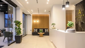 A modern reception area with a reception desk, seating area, and potted plants. - Anesea City (Heraklion)