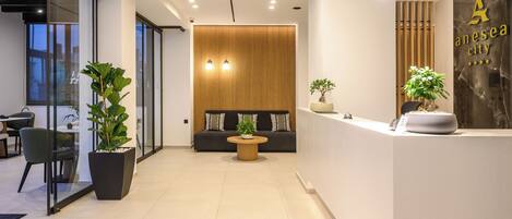 A modern reception area with a reception desk, seating area, and potted plants.