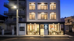 A modern hotel with a two-story structure, large windows, and a visible restaurant area with outdoor seating. - Anesea City (Heraklion)
