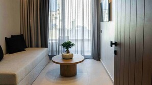 A modern room with a sofa, a round coffee table with a plant, and a sliding door. - Anesea City (Heraklion)